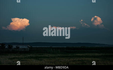 Cime di stormclouds oltre le montagne dei Carpazi in Romania sono illuminate dal sole al tramonto Foto Stock