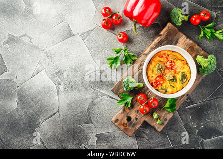 Frittata con broccoli in forma di ceramica. Frittata con i broccoli, dolci peperoni e pomodori in due forme ceramiche per la cottura. Omelette italiano con v Foto Stock