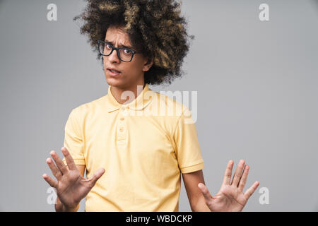 Foto di perplesso uomo caucasico con acconciatura afro gesticolando arrestare e mostrando la sua palme isolate su uno sfondo grigio Foto Stock