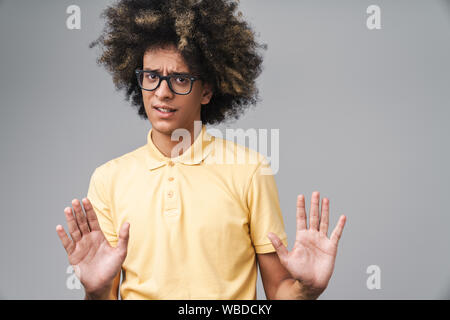 Foto di ansia uomo caucasico con acconciatura afro gesticolando arrestare e mostrando la sua palme isolate su uno sfondo grigio Foto Stock