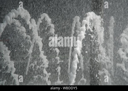 Fontana della retroilluminazione di sun. Le fontane zampillanti fonti di acqua frizzante dal tubo in posizione di parcheggio. Foto Stock