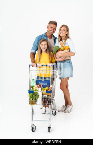 Lunghezza completa di una famiglia allegra indossare abbigliamento casual in piedi isolato su sfondo bianco, i negozi di generi alimentari insieme, borse e zaini e tro Foto Stock