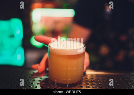 Il barista del bar rende la fiamma su un cocktail con buccia di arancia close up Foto Stock