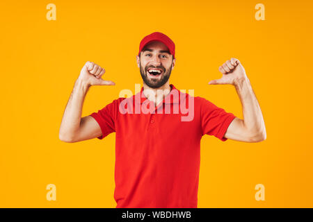 Ritratto di giovane uomo di consegna in t-shirt rossa e cappuccio sorridente e puntando le dita in se stesso isolato su sfondo giallo Foto Stock