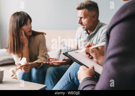 Foto di angry irritato giovane uomo e donna una conversazione con lo psicologo sulla sessione di terapia in camera Foto Stock