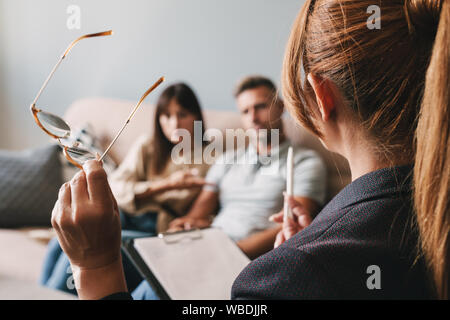 Foto di gravi caucasian giovane uomo e donna una conversazione con lo psicologo sulla sessione di terapia in camera Foto Stock