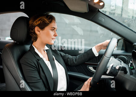 Imprenditrice alla guida di una vettura. Giovani donne in abbigliamento formale tenendo un volante. Foto Stock