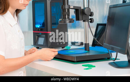 Lavoratore di sesso femminile nel controllo di resina LCD / DLP / SLA stampante 3D nel laboratorio di tecnologia Foto Stock