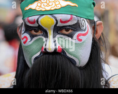 Partecipante in costume tradizionale con faccia dipinta a Bangkok il nuovo anno cinese street parade pone per la fotocamera. Foto Stock