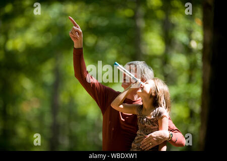 Nonno e nipote di guardare attraverso un telescopio giocattolo nei boschi Foto Stock