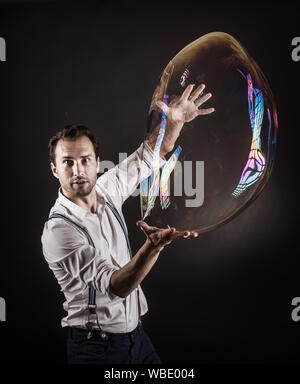 Artista tenere grandi bolle di sapone nelle sue mani. Bubble studio mostra concetto. Foto Stock