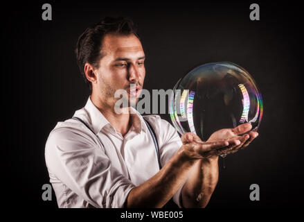 Artista tenere grandi bolle di sapone nelle sue mani. Bubble studio mostra concetto. Foto Stock