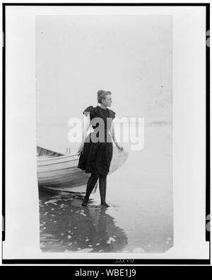 Frances Benjamin Johnston, ritratto a figura intera, in piedi sul bordo dell'oceano, in costume da bagno, con la mano sinistra sulla barca, rivolto verso destra Abstract/medio: 1 stampa fotografica. Foto Stock