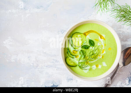 Vegano cetriolo freddo minestra in crema in una ciotola bianco su sfondo grigio. Foto Stock