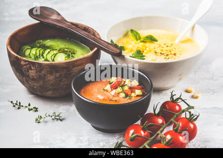 Tre differenti crema di verdure minestre in bocce su sfondo grigio. Il mais, il cetriolo e gazpacho zuppe. Foto Stock