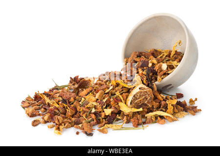 Cumulo di frutta secca di infusione del tè con arance e fragole miscelato con foglie di tè e un assortimento di erbe in tazza di tè su sfondo bianco Foto Stock