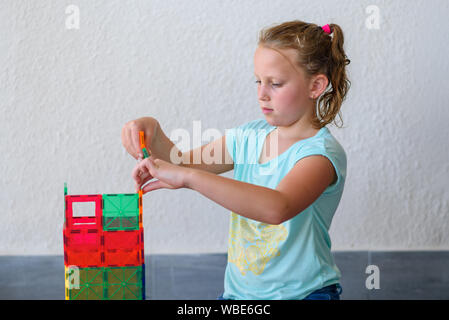 Bella ragazza adolescente giocando con un sacco di colorati di materia plastica in blocchi costruttore e costruisce la casa. Foto Stock