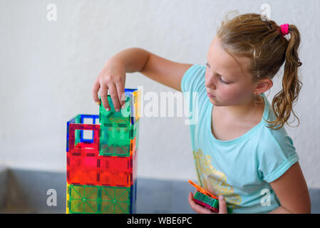 Bella ragazza adolescente giocando con un sacco di colorati di materia plastica in blocchi costruttore e costruisce la casa. Foto Stock