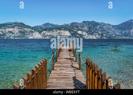 Dock in legno aggettante internamente al turquosie acqua del lago di Garda Foto Stock