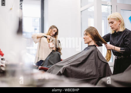 Bella donna di pettinatura dei capelli bagnati. stylist spazzolare i capelli donna in salone. Parrucchiere di servire il cliente. Professional giovani parrucchiere lavora con pettine Foto Stock