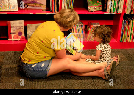 Lettura della madre per il suo bambino sul floorin l'angolo di un negozio di libri Foto Stock