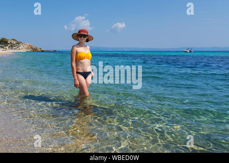 Moda giovane donna su Platanitsi esotica spiaggia di Sarti, Sithonia, Grecia con acqua cristallina e spettacolari forme delle rocce Foto Stock