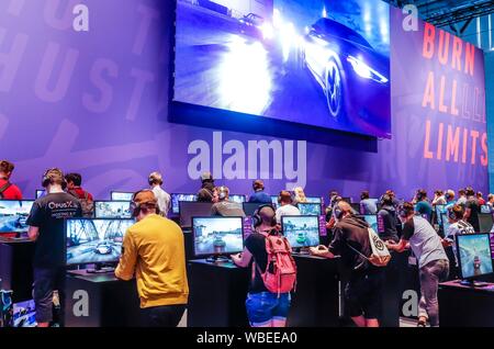 Gli adolescenti in Need for Speed car racing game di fronte a schermi, fiera per computer e video games gamescom di Colonia, nella Renania settentrionale-Vestfalia, Germania Foto Stock