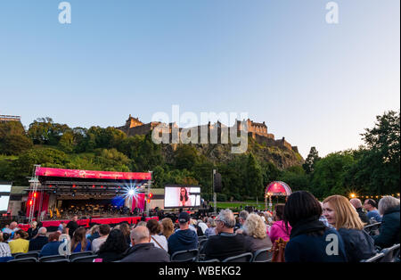 Edimburgo, Scozia, Regno Unito, 26 agosto 2019. Edinburgh International Book Festival. Il FEI 2019 volge al termine con la sua tradizionale finale, la Vergine denaro sponsorizzato concerto di fuochi d'artificio da Scottish Chamber Orchestra in Ross teatro in Princes Street Gardens, dotate di mezzo-soprano Catriona Morison. Edinburgh Castle Rock fornisce sullo splendido sfondo per i fuochi d'artificio. La gente in attesa per il concerto per iniziare Foto Stock