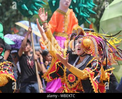 Davao City, Philippines-August 2014: Streetdancers in costumi colorati con la folla in streetsides presso il festival Kadayawan. Foto Stock