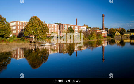 Un xix secolo mulino tessile è stato rinnovato per un uso moderno, visto riflesso nel fiume vicino a Exeter, New Hampshire Foto Stock