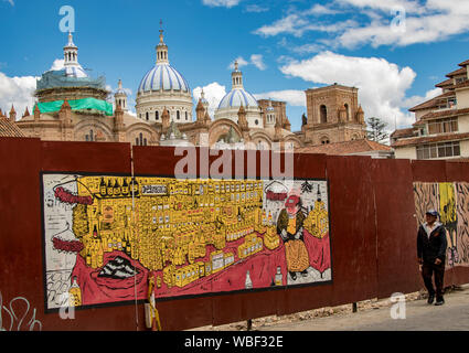 Cuenca, Ecuador, Dic 24, 2017 - uomo cammina passato costruzione barriera con murale dipinto e le cupole della cattedrale in background Foto Stock