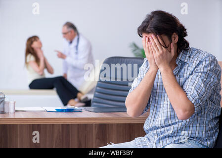 La giovane coppia visitando il vecchio medico maschio Foto Stock