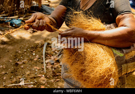Isola di Monroe, INDIA, MAR 15, 2018: Le donne di spin i capelli di noce di cocco con la mano, che si trasforma in una forte corda Foto Stock