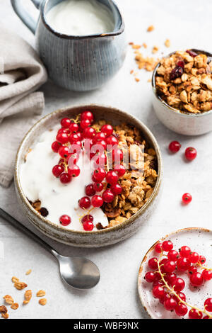 Crunchy granola con lo yogurt naturale e rosse bacche Ribes. Pulire mangiare, dieta e fitness concetto di menu. Il cibo della colazione ancora vita Foto Stock