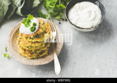 Frittelle di vegetali di zucchine, cavolo, Patate servita con panna acida e di coriandolo fresco. Copia dello spazio. Immagine dai toni Foto Stock