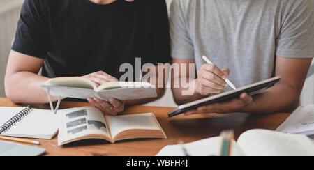 Vista ravvicinata dei due proprietari a discutere il progetto insieme a libri e tablet Foto Stock