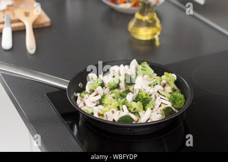 Cuocere i broccoli e funghi in padella sul fornello. Salutare mangiare vegetariano concetto. Foto Stock