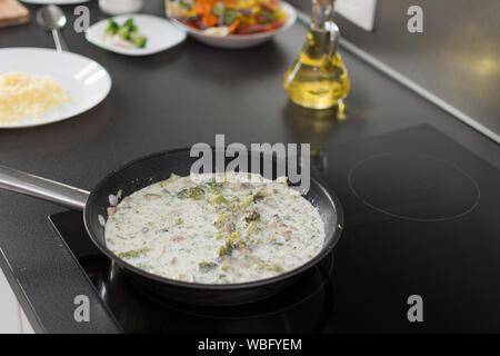 Salsa cotta con i broccoli e funghi in padella sul fornello. Salutare mangiare vegetariano concetto. Foto Stock