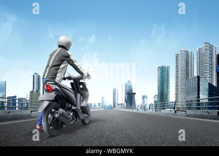Vista posteriore del motociclo asiatici taxi uomo spinge la sua motocicletta sulla strada asfaltata sulla midtown Foto Stock