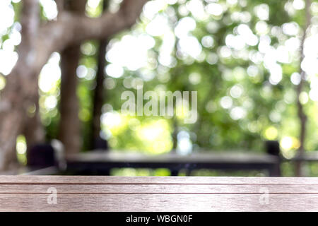 Svuotare legno marrone tavolo su blur abstract giardino verde con bokeh di fondo. Modello mock up per la visualizzazione del prodotto. Foto Stock