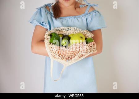 I giovani adulti mani stringa attesa borsa a rete riempita con frutti di colore verde. .Concetto di vita naturale con rifiuti zero o riutilizzabili eco borsa per lo shopping. Foto Stock