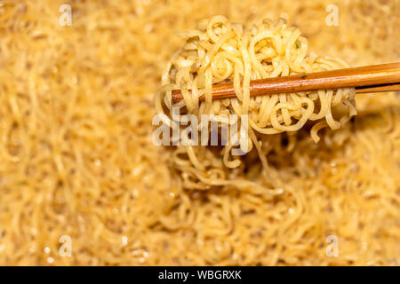 Close up tagliatelle istante in una ciotola. Mano che tiene le bacchette di bambù la tagliatella. Foto Stock