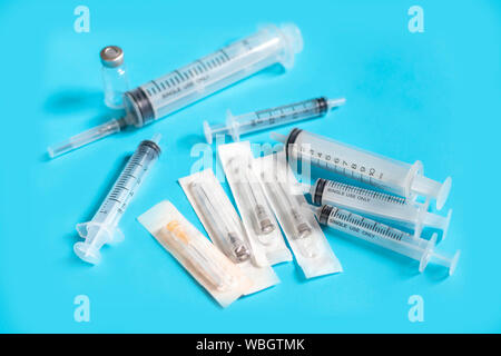 Fiale con farmaci e ago di iniezione su sfondo blu. Siringhe multipli. Siringhe che pacco insieme. Foto Stock