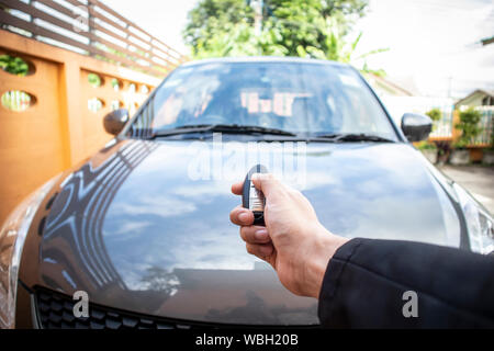 Imprenditore aprendo la sua auto porta con premendo il pulsante sul comando a distanza di chiave. Foto Stock