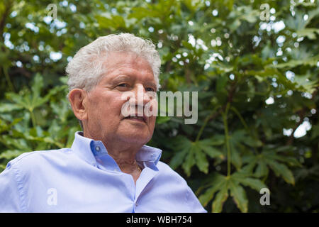 Ritratto di un vecchio bianco uomo grigio con capelli ricci e la maglietta blu, guardando lontano con espressione serena. Foto Stock