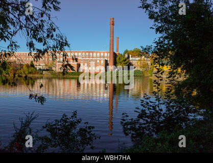 Un xix secolo mulino tessile è stato rinnovato per un uso moderno, visto riflesso nel fiume vicino a Exeter, New Hampshire Foto Stock