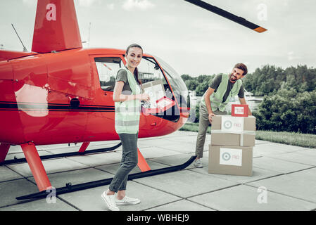 Gli operatori umanitari in piedi vicino elicottero inviare pacchi Foto Stock