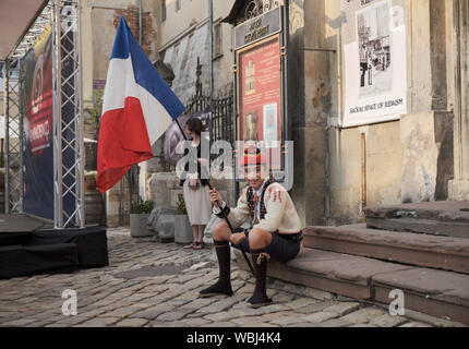 Ritratto di giovane ragazzo francese vestito in couserans abiti folcloristici seduti sul passo. Portabandiera per la parata di Etnovyr festival di strada di Leopoli. Foto Stock