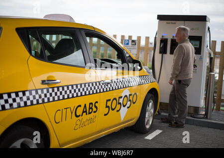 James Leaburn, taxi driver, carica il suo veicolo elettrico taxi a Princes Street la ricarica elettrica ferroviaria, uno dei tre di tali stazioni in città, in Scozia, il 14 agosto 2019. Foto Stock