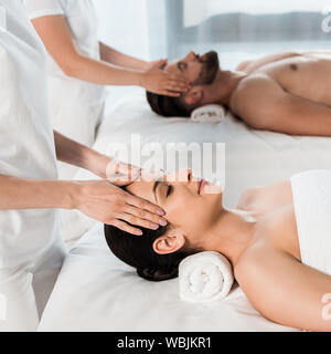 Vista ritagliata di massaggiatori facendo massaggi per donna e uomo nel centro spa Foto Stock